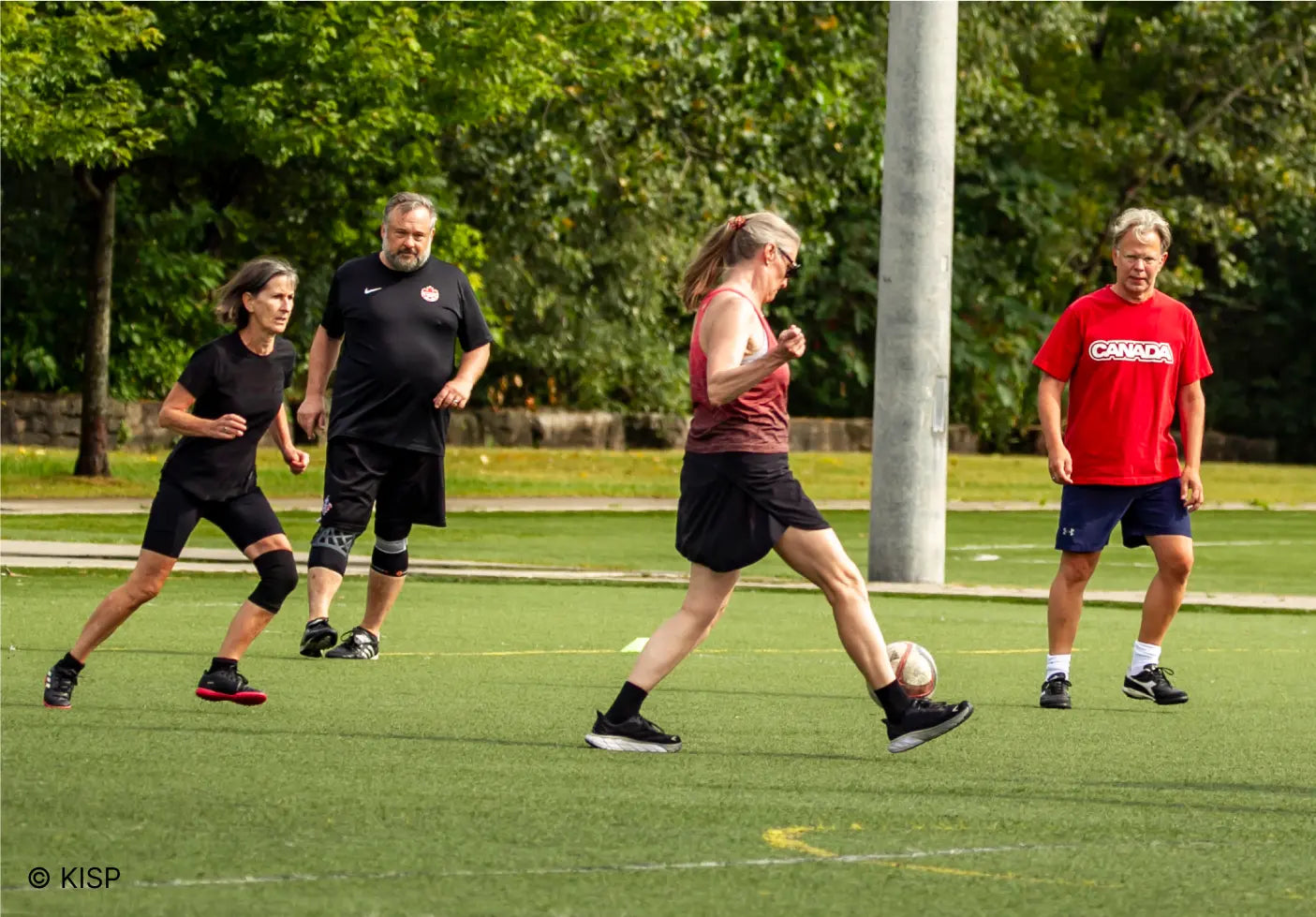 Two women and two men playiong walking soccer on a turf field in Toronto
