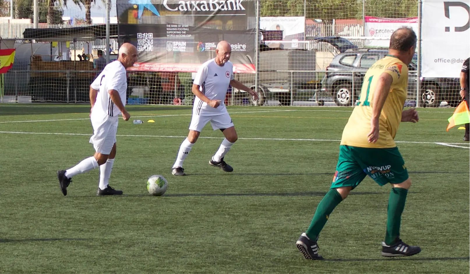 Three men playing soccer on a field with a visible 'CaixaBank' advertisement in the background.