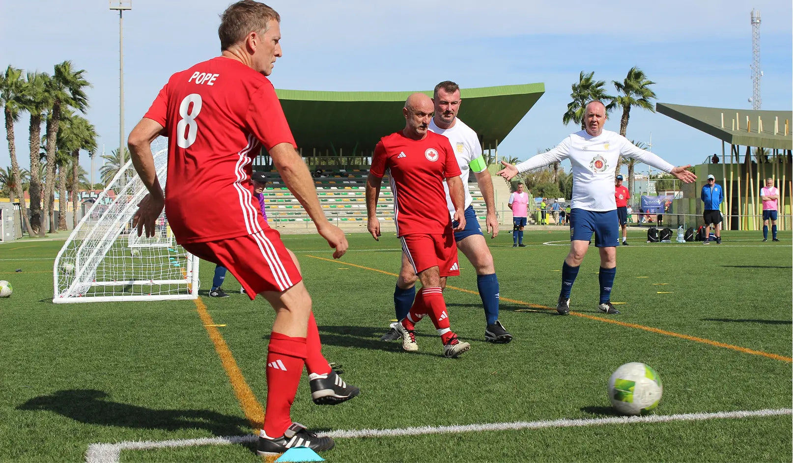 Soccer game in progress on a field with players in red and white uniforms.