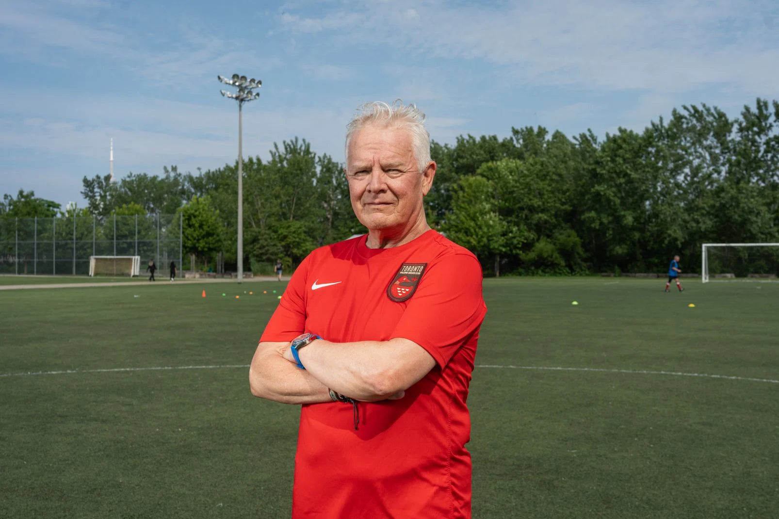 Toronto Walking Soccer player in their red uniform stands in front of a turf field.