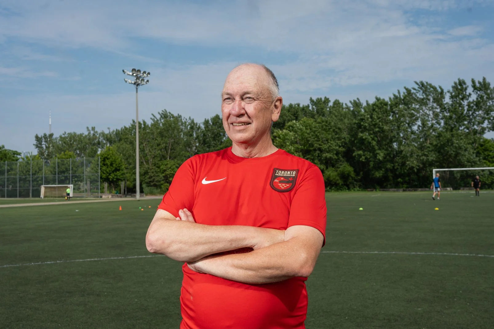 Toronto Walking Soccer player in their red uniform stands in front of a turf field.