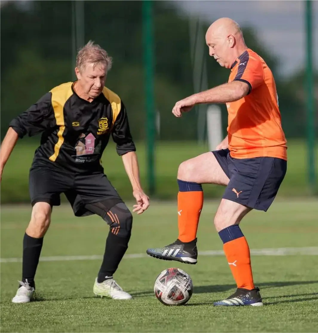 Older adult men playing walking soccer on a turf field